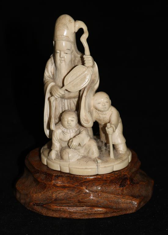 A Japanese ivory group of a sage and attendants, 10cms with hardwood stand